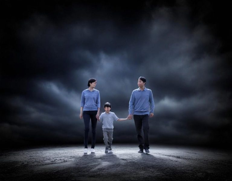 Une famille marchant main dans la main sous un ciel sombre et nuageux.