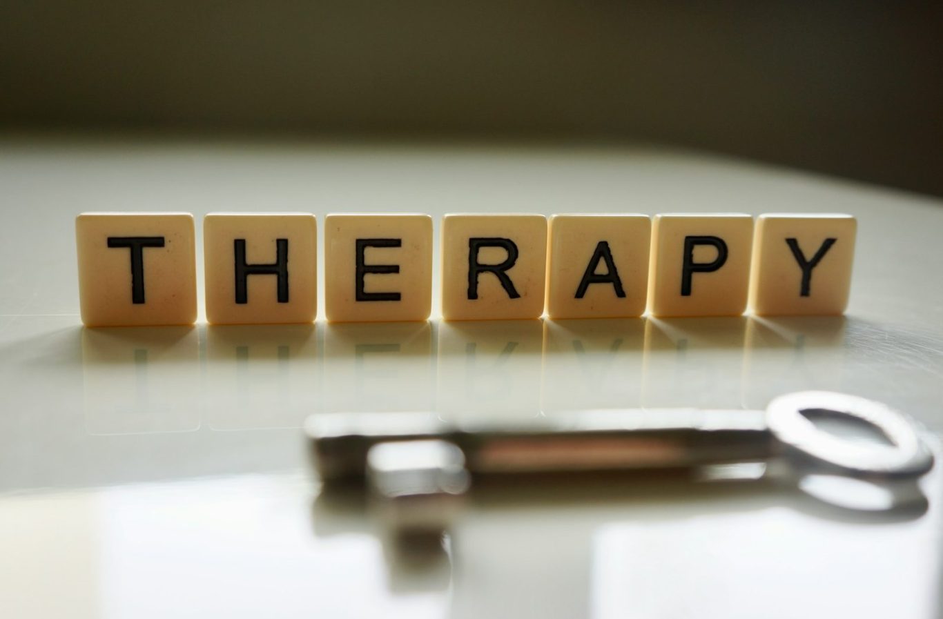 Lettres en bois formant le mot "THERAPY" avec une clé en métal à côté.
