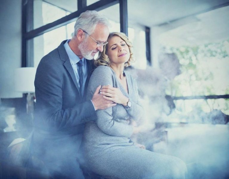 Un homme et une femme, en tenue de bureau, se tiennent l'un l'autre dans un environnement calme.