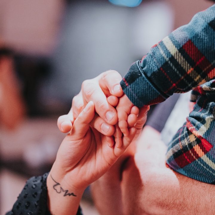 Deux mains se rejoignent, une adulte et une enfant, dans un moment tendre.