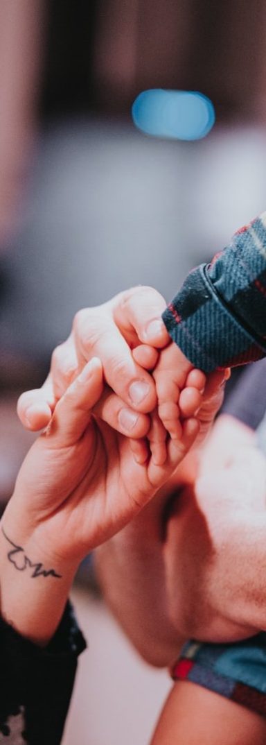 Deux mains entrelacées, une main avec un tatouage, dans un environnement flou.